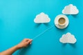 Hand holding coffee cup in shape of balloon on blue paper background