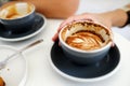 Hand holding coffee cup on white table at cafe background, top view, food and drink concept