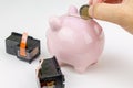 Hand holding a coin next to a piggy bank and two ink cartridges. Cost of ink concept Royalty Free Stock Photo