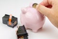 Hand holding a coin next to a piggy bank and two ink cartridges. Cost of ink concept Royalty Free Stock Photo