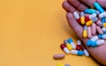 Hand holding colorful capsule pills on yellow background. Antibiotic drug overuse concept. Antibiotic drug resistance and superbug