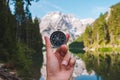 hand holding compass view of mountain lake on background