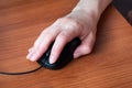 Hand holding computer mouse. Close up. Wooden table