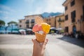Hand holding cone with colorful delicious italian gelato ice-cream in Menaggio town near Como lake Royalty Free Stock Photo