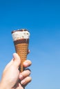 Hand holding a cone of ice cream with blue sky background Royalty Free Stock Photo