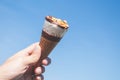 Hand holding a cone of ice cream with blue sky background Royalty Free Stock Photo