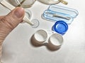 Hand holding a contact lens with lens case and cleaning tools on a white surface during a daily routine Royalty Free Stock Photo