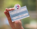 Hand holding COVID 19 vaccination card and sticker. UK