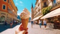 Hand holding a creamy gelato ice cream cone on a sunny street, with a blurred city backdrop invoking summer vibes and leisure