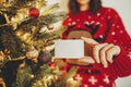 hand holding credit card close-up on background of golden beautiful christmas tree with lights in festive room. christmas Royalty Free Stock Photo