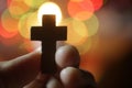 Hand holding a cross. On blurry background of colorful bokeh lights. Love passion, faith and hope concept Royalty Free Stock Photo