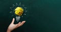 Hand holding crumpled paper with Light bulb on blackboard