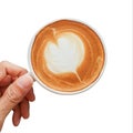 Hand holding Cup of coffee latte shape of heart pattern isolated on white background Royalty Free Stock Photo