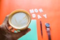 Hand holding cup of Coffee with monday ,wood text minimalist layout  On orange background. Royalty Free Stock Photo