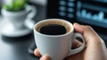 Hand holding cup of coffee in office setting Royalty Free Stock Photo