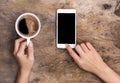 Hand holding cup of coffee and smart phone