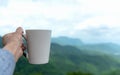 Hand holding Cup coffee and tea with steam on wood table over winter mountains nature landscape with sunlight. Royalty Free Stock Photo