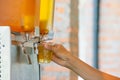 The hand holding the cup plastic flush tea from Juice Dispensor Royalty Free Stock Photo