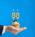 Hand delivering birthday cupcake - Candle number 88 on blue background