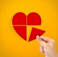 Hand holding cut out heart paper shape on yellow background Royalty Free Stock Photo