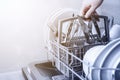 Hand holding cutlery basket with clean cutlery in open dishwasher in kitchen Royalty Free Stock Photo