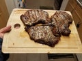 Hand holding cutting board with grilled beef steaks in kitchen Royalty Free Stock Photo