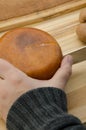 Hand holding and cutting a Cheese wheel