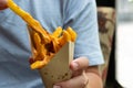 Hand holding delicious french fries topping with cheddar cheese cream and crispy bacon on close up side view Royalty Free Stock Photo