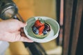 Hand holding delicious fresh homemade fruit tart with raspberries, blueberries, blackberries, cherries and red currants in coffee Royalty Free Stock Photo