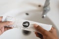 Hand holding a dental kit set against toilet wash basin.