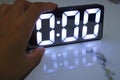 A hand holding a digital clock showing 0:00 glowing on the glossy marble surface Royalty Free Stock Photo