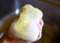 Hand holding a dishwashing sponge with dishwashing liquid bubble