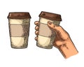 Hand holding a disposable cup of coffee with cardboard holder and cap.