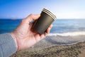 Hand holding disposable plastic cups on beach: pollution concept Royalty Free Stock Photo