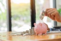 Hand holding a dollar in a jar with a pile of coins on the table, the idea of saving money for the future. Royalty Free Stock Photo