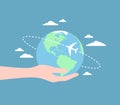 Hand holding Earth globe with an airplane flying around it and clouds on a blue background. Flat vector illustration Royalty Free Stock Photo