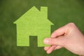 Hand holding eco house icon concept on the green grass background Royalty Free Stock Photo