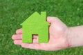 Hand holding eco house icon concept on the green grass background Royalty Free Stock Photo