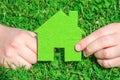 Hand holding eco house icon concept on the green grass background Royalty Free Stock Photo