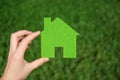 Hand holding eco house icon concept on the green grass background Royalty Free Stock Photo