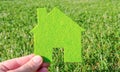 Hand holding eco house icon concept on the green grass background Royalty Free Stock Photo