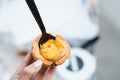 Hand holding an egg tart with a spoon Royalty Free Stock Photo