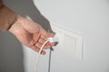 Hand holding electric plug into a power outlet Royalty Free Stock Photo