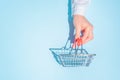 hand holding empty metal shopping basket.