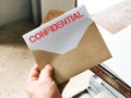 Hand holding envelope with white card written text CONFIDENTIAL. Royalty Free Stock Photo