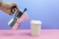 Hand holding espresso maker pouring coffee into paper cup