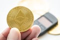 Holding ETH ethereum gold coin with hardware wallet in background