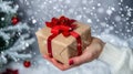 Hand holding a festive holiday gift against a solid silver background Royalty Free Stock Photo