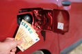 A Hand holding five fifty euro banknotes in front of a car's fuel tank Royalty Free Stock Photo