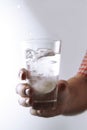 Hand holding fizzing glass of water with tablet inside, close-up